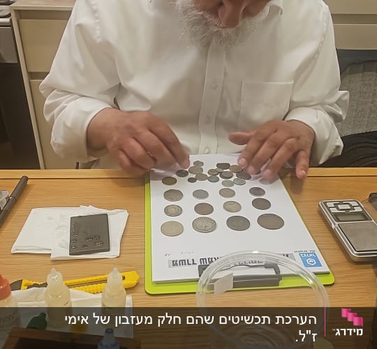 אדם בוחן מטבעות על שולחן עם כלים שונים